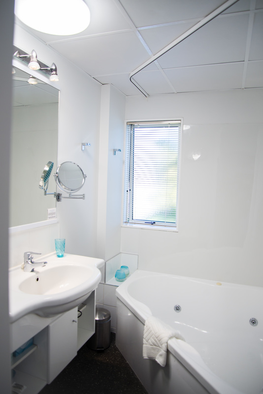A bathroom with a sink, mirror and spa bath